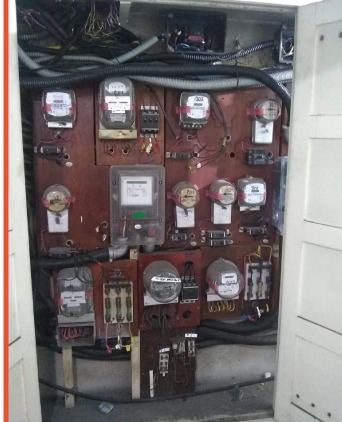 PC de luz antigo com fiação exposta e medidores desorganizados, fora do Padrão Light — exemplo real de instalação condenada pelo Corpo de Bombeiros desde 1990